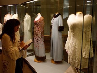 Photo of student writing while looking at a fashion museum